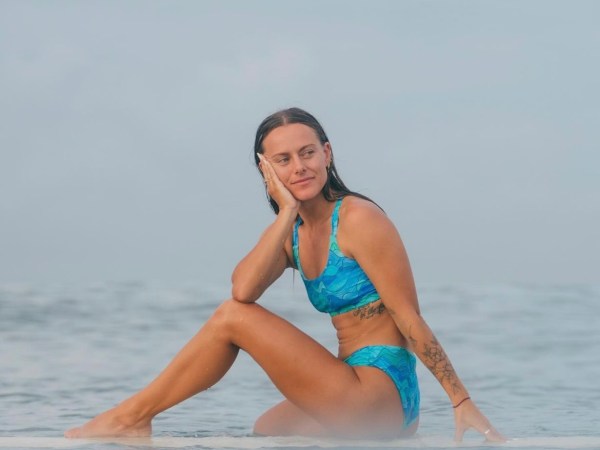 a woman sitting next to a body of water