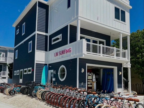Three-story blue building with LBI Surfing sign and rows of parked bicycles outside.