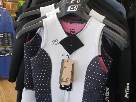 Hanging wetsuits in a shop, featuring a white and black polka dot design.
